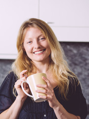 Beautiful blond having coffee in her kitchen