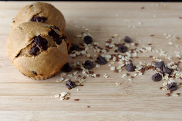 Homemade muffins on wooden table with oats and seeds