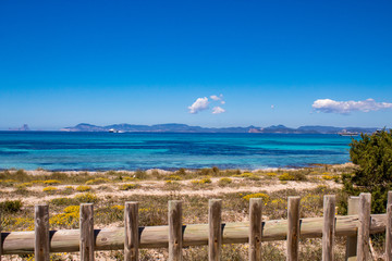 Typical balearic natural reserve wooden fence, and blue mediterranean sea on the background; Formentera Island, Spain