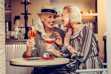 Laughing grey-haired ladies being excited with their meeting