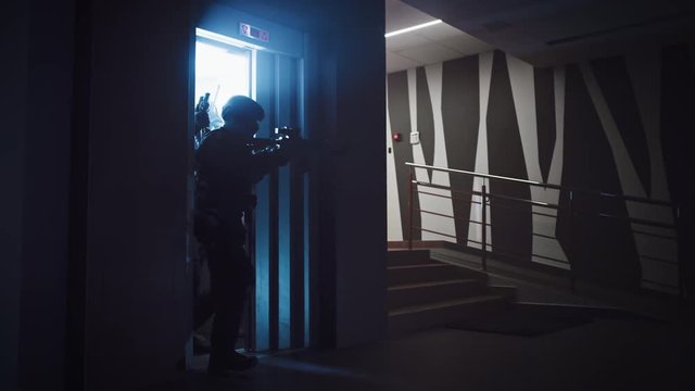 Masked Squad of Armed SWAT Police Officers Move Out from the Elevator and Storm the Corridor of an Office Building. Soldiers with Rifles and Flashlights Move Forwards and Cover Surroundings. 