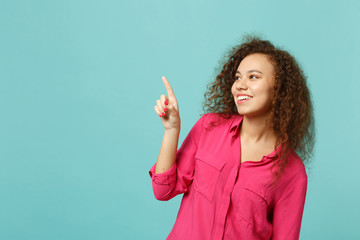 Portrait of joyful african girl in casual clothes looking, pointing index finger aside isolated on...