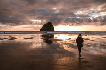 woman running on beach to haystack rock at sunset - 265498803