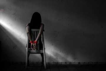 Young woman sitting on chair and  tied up with rope ,Victim woman tied with red rope sit on chair...