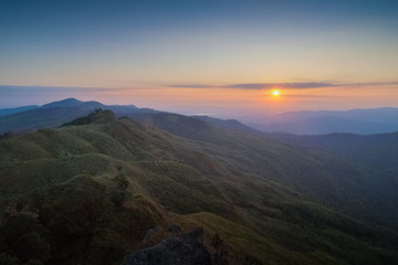 Mountain view morning above many hills and green forest around with soft fog with colorful red sun light in the sky background, sunrise at top of Phu Langka Forest Park, Phayao, Thailand.