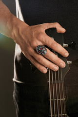 Cropped shot of man's hand, touching headstock of guitar. The guy is wearing massive ring in view...