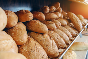 Fresh delicious loafs of bread in row on shelves ready for sale. Bakery interior.