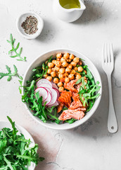 Spicy chickpeas, baked salmon, crispy radish, arugula salad on a light background, top view
