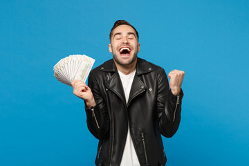Young unshaven man in black leather jacket white t-shirt holding fan of cash money in dollar...