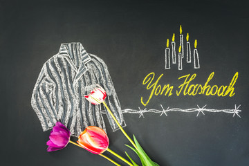 Chalk inscription Yom HaShoah (Holocaust Memorial Day) and striped prison uniform of concentration camp prisoners drawn on a chalk board