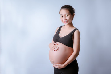 The side of the body of a pregnant woman wearing a black shirt With hands holding the belly on the White Blackground