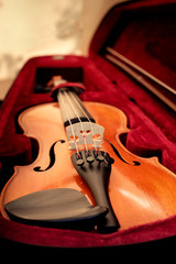 Violin and bow in dark red case. Close up view of a violin strings and bridge © lusyaya