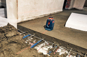 Laying blue pipes for floor heating at the construction site.