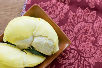 fresh Monthong durian on brown wooden and red fabric background, Tropical seasonal fruit, King of fruit from Thailand.
