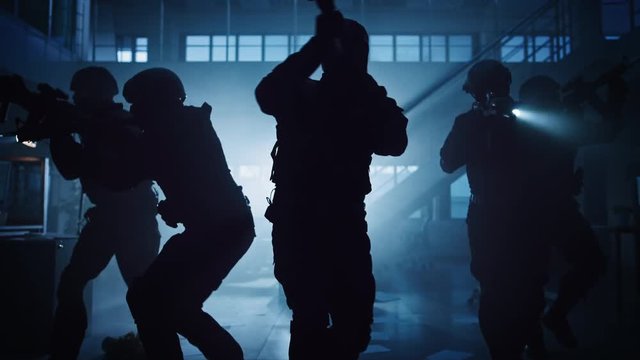 Masked Fireteam of Armed SWAT Police Officers Storm a Dark Seized Office Building with Desks and Computers. Soldiers with Rifles and Flashlights Move Forwards and Cover Surroundings.