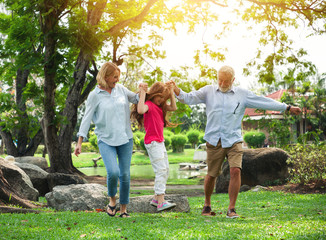 Fototapeta premium Happy grandfather, grandmother with granddaughter playing in summer day, Family relaxing in the garden
