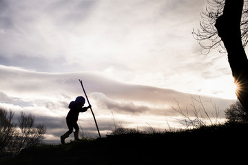 Silhouette of girl hiking hill against cloudy sky during sunset