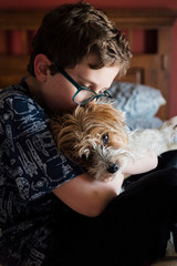 Boy kissing yorkshire terrier at home