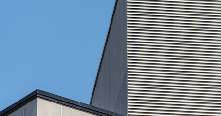 striped wall of a gray tall building against a blue clear sky