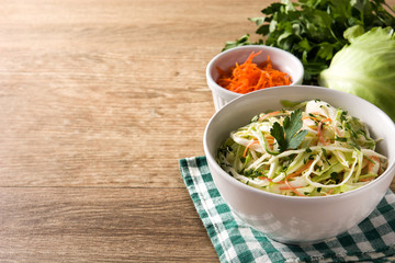 Coleslaw salad in white bowl on wooden table. Copyspace