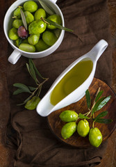 green olives, olive branch and olive oil on a dark wooden board