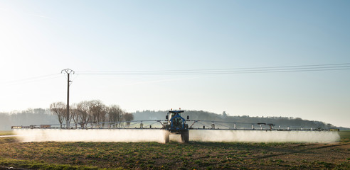 tracteur agricole qui pulvérise des produits chimiques sur un champ