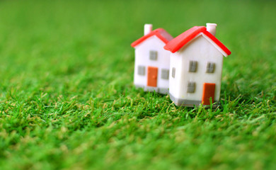 Real estate property concept with two little toy houses on a green artificial grass