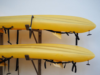 two yellow kayaks are stored outside.