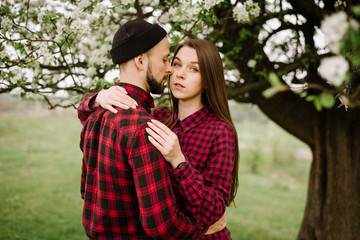 Young romantic couple walking on the meadow and blooming tree and have fun