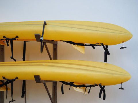 two yellow kayaks are stored outside.