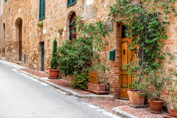 Fototapeta na wymiar San Quirico D'Orcia, Italy Street empty road in small historic medieval town village in Tuscany during summer day stone architecture and garden