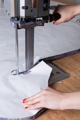 female hands cut fabric with electric knife, garment factory