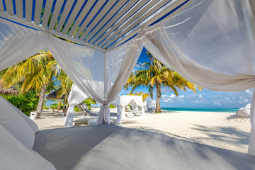Fototapeta na wymiar White beach canopies. Luxury beach tents at a resort. Wonderful view of beach scenery, luxury vacation and travel background concept