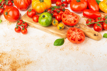 Selection of organic large heirloom and cherry tomatoes on white cream brown concrete background, selective focus