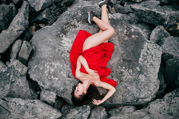 Sexy beautiful  brunette swag glamorous babe lying on stones outdoor in summer.  Top down lifestyle portrait of naked charming woman relaxing under red cover. Passionate female posing at nature.