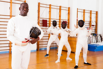 African american male fencer in uniform standing with mask and foil