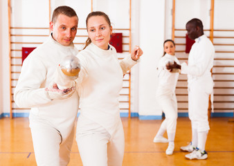 Girl fencer exercising new techniques with trainer  indoors