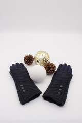 Blue gloves, white and golden Christmas balls and two pine cones on a white background. New Year’s and Christmas Concept.