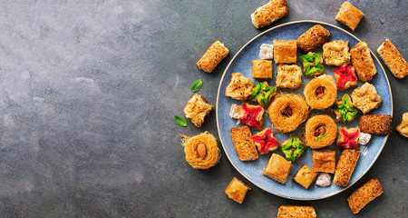 Traditional arabian oriental sweets baklava on gray rustic background. Top view, copy space.
