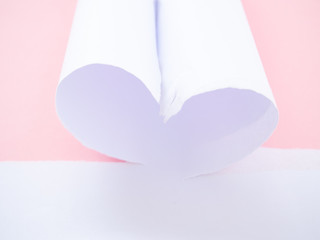 A torn white paper heart-shaped isolated in pastel pink