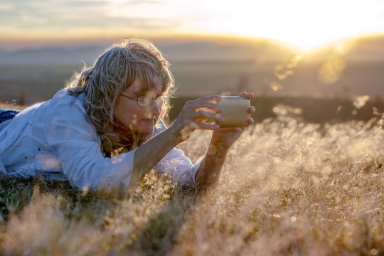 Woman taking (selfie) pictures with the smartphone in sunset
