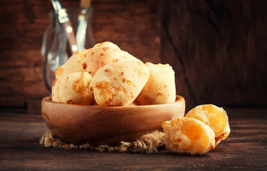 Cheese buns in wooden bowl, rustic kitchen table background, copy space, selective focus