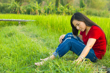 Teen girl Asian sitting in rice field thinking and smiling happily reminded of past great story