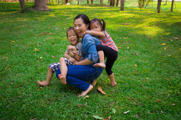 Naklejka na ściany i meble Lifestyle portrait mom son and daughter in happiness at the outside in the meadow, Funny Asian family in a green park