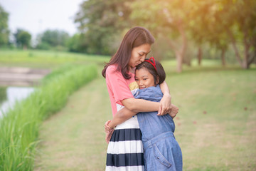 Asian mother and little cute child playing together outdoors.Happy family in mother's day concept,I Love you best mom.Mum and adorable little daughter greeting ,proud and hug together in park.