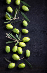 green olives and olive branch on a dark wooden board