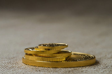 A pile of gold coins of various sizes on a background of rough wood texture.