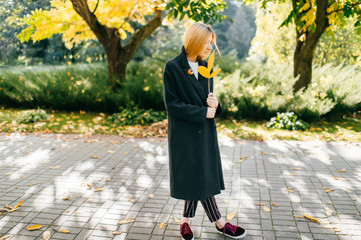 portrait of full-length pensive girl in black coat with Frond in hand