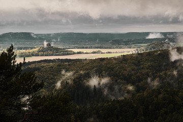 Deadpan dark misty rainy morning landscape with the sand rocky montains in Czech Saxon Switzerland in autumn colors