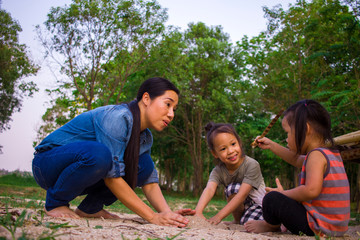 Lifestyle portrait mom son and daughter  playing with sand, Funny Asian family in a park